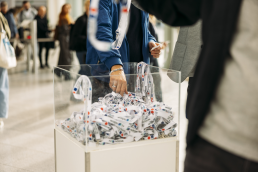 DMEXCO Lanyards, Frau greift sich einen Lanyard aus der Kiste am Eingang der Messe