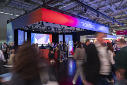 Blick auf die B&uuml;hne der Techstage der DMEXCO, Menschen die unscharf fotografiert sind und an der B&uuml;hne vorbei laufen