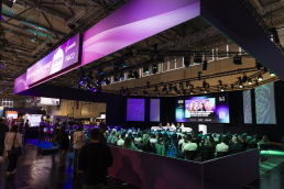 Agency Stage, Bühne in Maganta-Farben der DMEXCO, Präsentation auf der Bühne, Besucherinnen und Besucher im Publikum, Aufbau der Bühnenwände, Bühnengestaltung