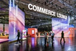 Commerce Lounge auf der DMEXCO Messen in Köln, Messehalle mit einem exklusiven Bereich, große bunte Banner, Menschen laufen unscharf durch die Aufnahme