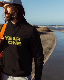Mann am Strand mit Sporttasche, Hoodie mit der Year One Grafik von Daimler Truck