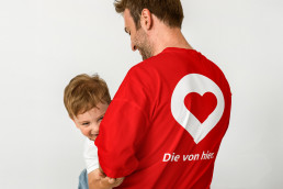 Mann mit seinem Kind trägt T-shirt mit dem Locator und dem Slogan der Kampagne die von hier der Kampagne Werra-Meißner