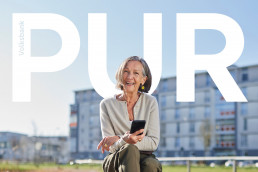 Volksbank Pur Kundin, Seniorin mit Handy in der Hand, Pur als Schriftzug über dem Bild