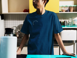 Junge steht in der K&uuml;che und tr&auml;gt ein dunkelblaues T-shirt der Organisation Cranach Kreis, Logo auf Brusth&ouml;he platziert