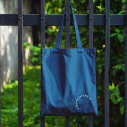 Blaue Tasche h&auml;ngt an einem Gartenzaun, Cranach Kreis Logo unten rechts auf der Tasche platziert